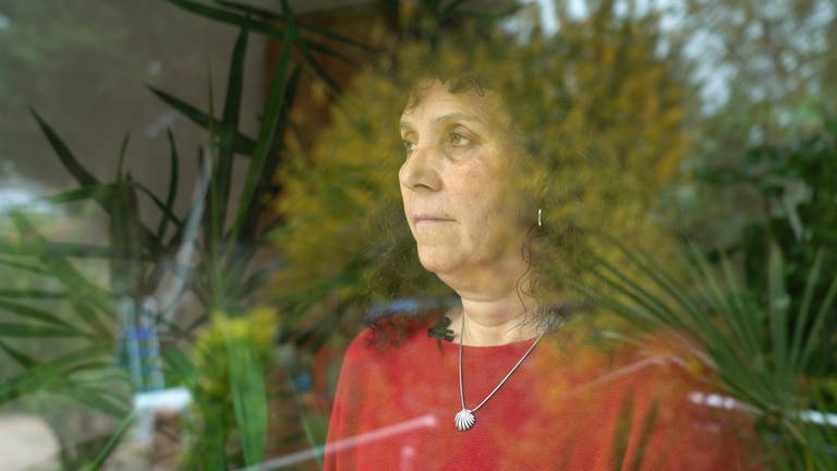 Traurige Frau steht an einem Fenster und blickt in die Ferne