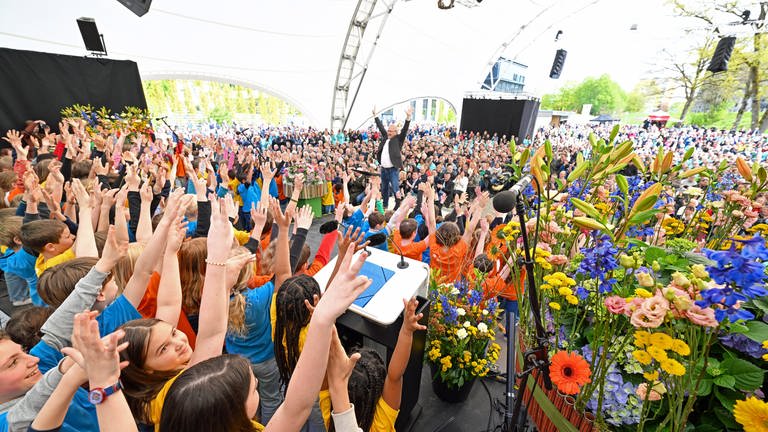Ein Projektchor mit dutzenden Kindern aus Wangen unter der Leitung von Dirigent Christian Feichtmair singt bei der Eröffnung der Landesgartenschau in Wangen im Allgäu. Hunderte Gäste kommen zur Eröffnung in das Open-Air-Zelt.