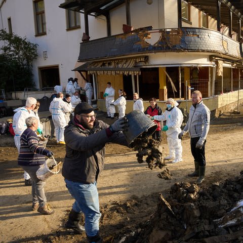 Helfer befördern Schlamm aus einem Haus in Altenahr im Ahrtal nach der Flutkatastrophe 