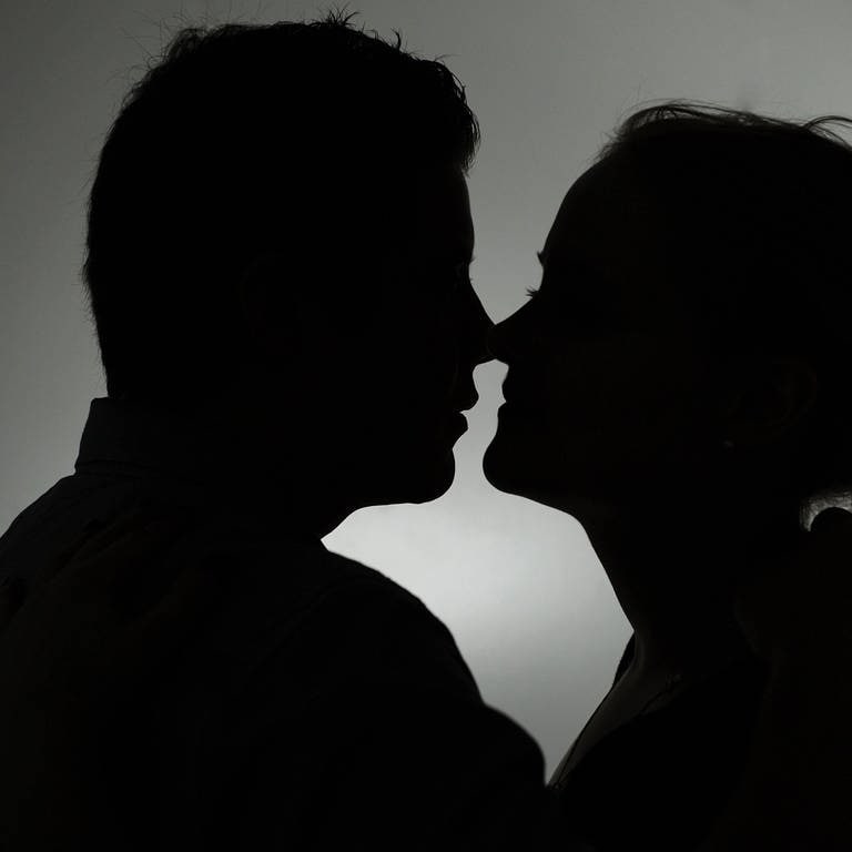 Ein Mann und eine Frau küssen sich. Immer wieder fallen Menschen auf der Suche nach der großen Liebe aber auf Betrüger herein. 