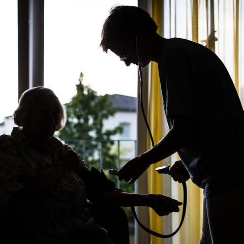 Eine Pflegekraft kümmert sich in einem Pflegeheim um eine ältere Dame
